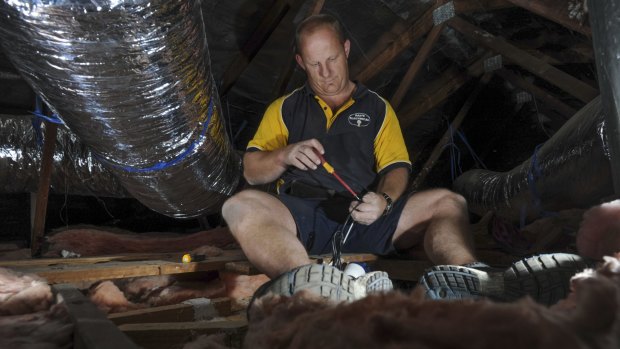 Electrician Paul Callaway in the roof space of a home in Weston. He says he has no doubt been in Mr Fluffy homes during his 20-year career.