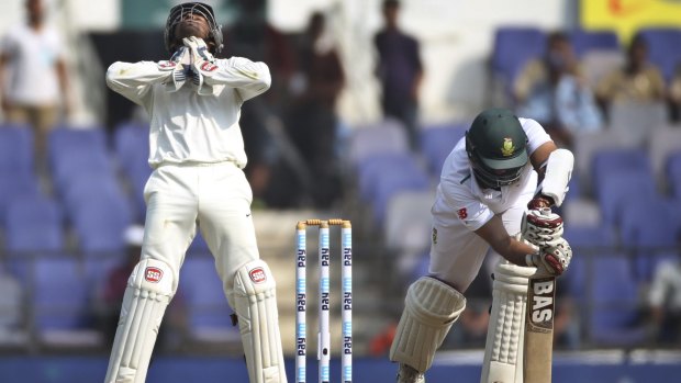 South Africa captain Hashim Amla plays forward defensively but misses the ball which goes through to Indian wicket-keeper Wriddhiman Saha.