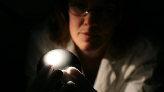 Optical engineer Katie Green examines a silicon sphere at the CSIRO's Australian Centre for Precision Optics. Counting the atoms in perfect silicon spheres could replace the definition of the kilogram.