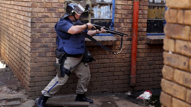 A police officer takes aim as they search a hostel in Johannesburg on Thursday.
