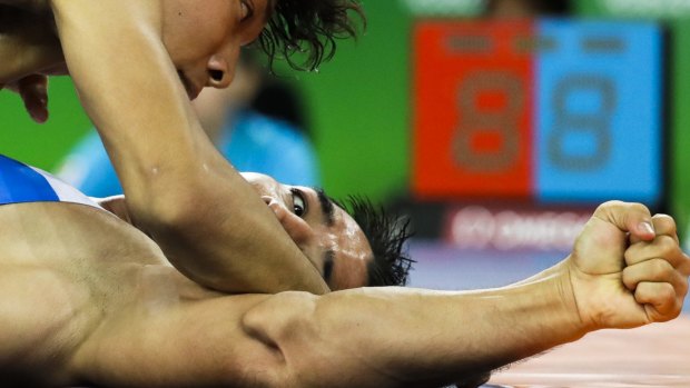 Australian wrestler Talgat Ilyasov looks to his injured arm as he competes against Japan's Sohsuke Takatani in the men's 74-kg freestyle competition