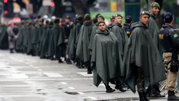 Brazilian military officers stand guard in rain gear along the route of the men's marathon at the 2016 Olympics in Rio .