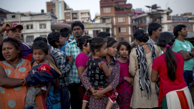 Residents of Kathmandu, who moved out in the open and set up temporary tents, stand in line to get emergency help.