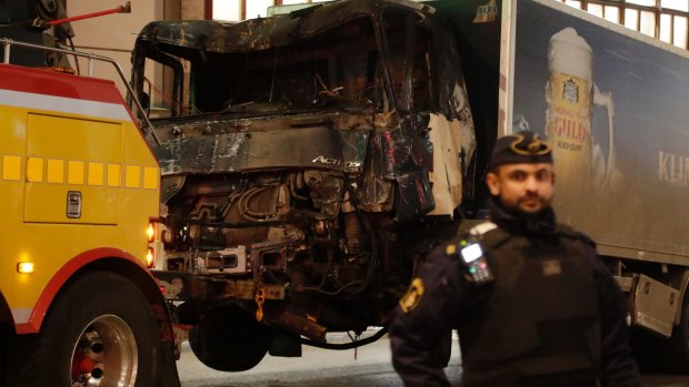A destroyed truck is towed away after it was driven into a department store in Stockholm on Friday.