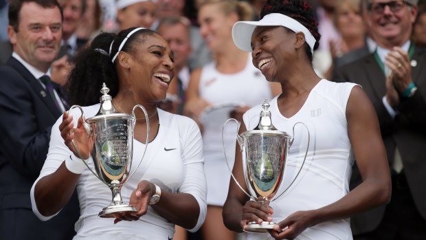 Winners are grinners: Serena and Venus Williams hold their trophies after winning the women's doubles final against Yaroslava Shvedova and Timea Babos.