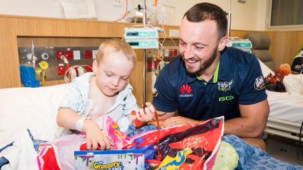 Raiders player Josh Hodgson and Kalten Nelson, 5, playing with new toys at the Canberra Hospital children's ward.