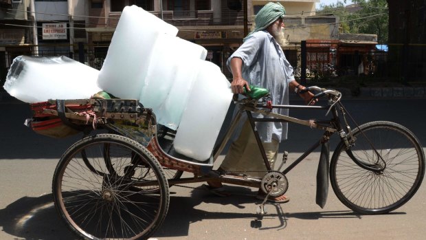 An Indian worker uses a ricksahw to transport ice from an ice factory in Amritsar.