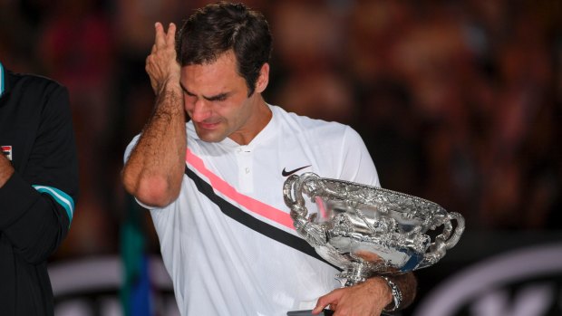 Roger Federer wipes away the tears as he holds the Australian Open trophy.