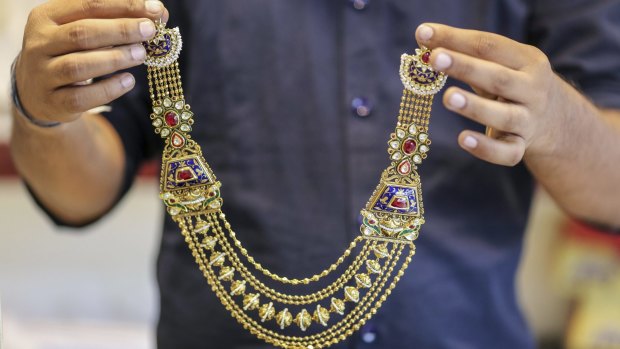 A sales assistant shows a gold necklace to a customer at the Umedmal Tilokchand Zaveri jewellery store in Mumbai on Monday.