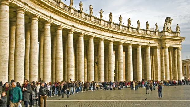 Visitors waiting in line along the Colonnade of the St Peter Square to enter into the St. Peter Cathedral in Rome, Italy.