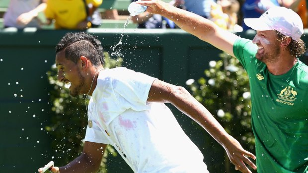 Nick Kyrgios makes a break for it as he cops a dousing.