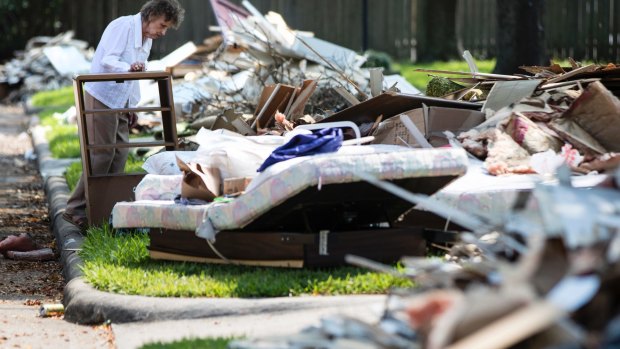 A resident views her flood-damaged possessions piled in the front yard in the aftermath of Hurricane Harvey in Houston. 
