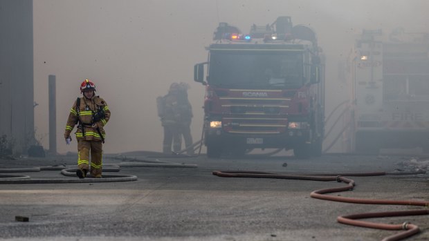 Firefighters work in thick smoke at a fire in a recycling plant in Coolaroo.