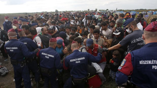 Hungarian police officers control the crowd as migrants try to board a bus in Roszke.