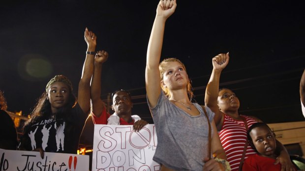 Mourners in Baton Rouge raise their fists during a night rally on Monday in honour of Alton Sterling, who was shot and killed by Baton Rouge police earlier this month.