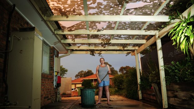 Kristel Shelley looks at the damage to her carport after a storm hits Queanbeyan.