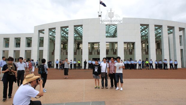 Tourists taking photos on the forecourt of Parliament House in Canberra.