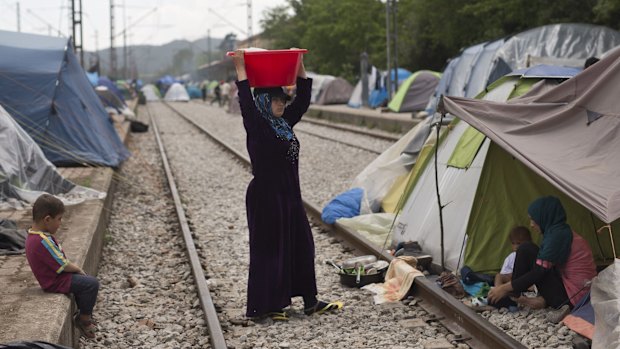 A woman walks along railway tracks at the makeshift refugee camp at Idomeni on Friday. 