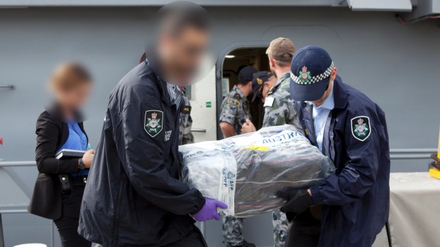 Australian Federal Police officers carry bags of cocaine.