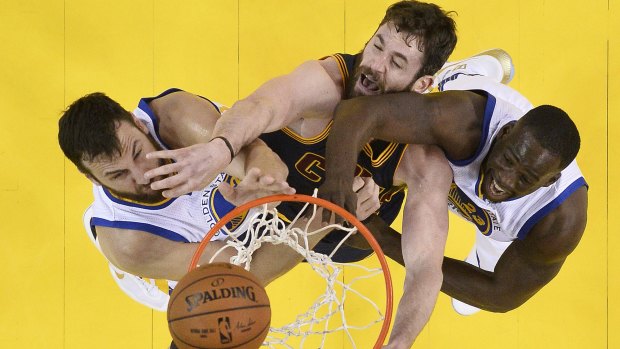 In the paint: Cleveland Cavaliers forward Kevin Love reaches for the ball between Golden State Warriors duo Andrew Bogut and Draymond Green.