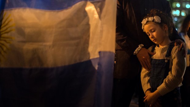 A child reacts as a woman holds an Argentinian flag next to her during a candle-lit walk to remember the victims in New York.