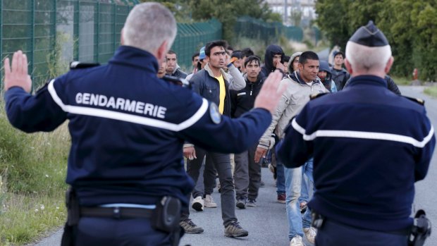 French gendarmes block migrants along a road to prevent them gaining access to train tracks which lead to the Channel Tunnel on Wednesday. 