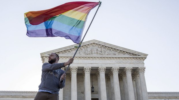 Vin Testa waves a gay rights flag in front of the Supreme Court.