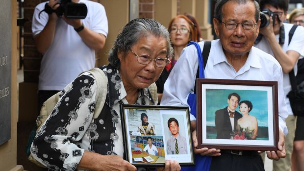 Min Lin's parents, Feng Qing Zhu (left) and Yang Fei Lin, outside the Supreme Court with photos of their murdered family members on Friday.