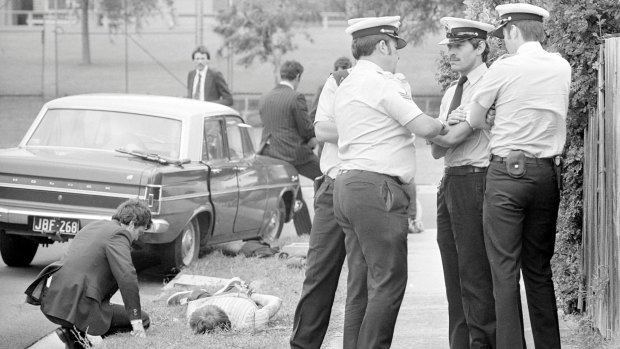Detectives watch over handcuffed suspect after a bank robbery in Coolaroo, Melbourne in 1977. The men were arrested after a high-speed police chase and gun battle. 