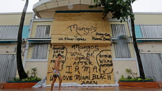 A beachgoer walks by a boarded restaurant at Miami Beach in anticipation of Hurricane Irma. 