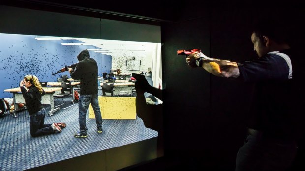 Paul Burns demonstrates the company's prototype mobile firing range, where police and soldiers must react to virtual scenarios. 