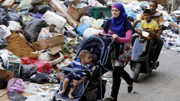Residents move past rubbish piled up along a street in Beirut this week. 