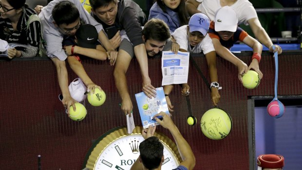 Fan favourite: Milos Raonic signs autographs after the match.