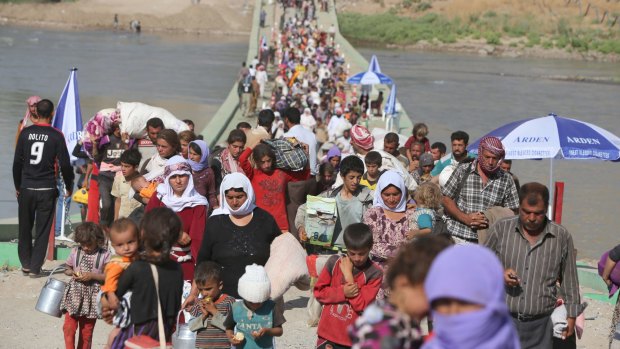 Displaced Iraqi Yazidis cross the Syrian-Iraqi border in  August.
