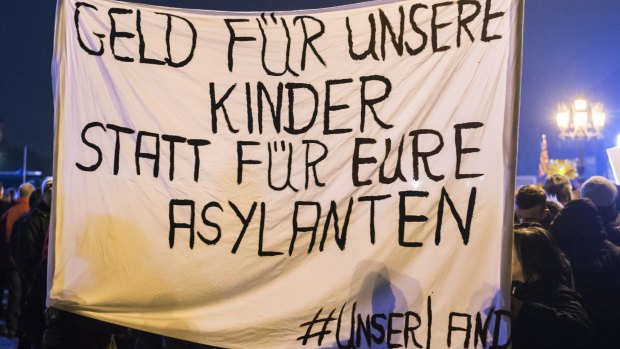 Protesters hold a banner during a Pegida demonstration. The banner reads in German: "Money for our children and not for your asylum seekers." 