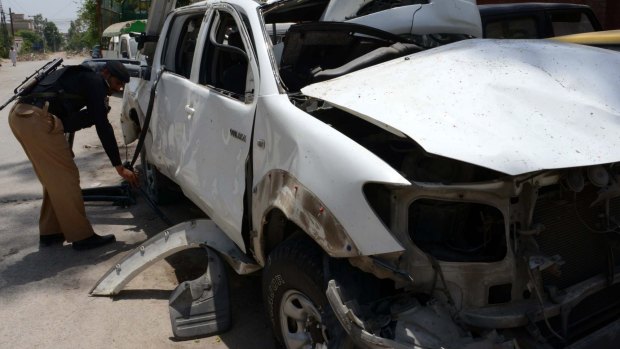 A Pakistani police official inspects a damaged security vehicle after a Taliban suicide bomb attack on a senior police officer in Peshawar on June 11, 2015. 