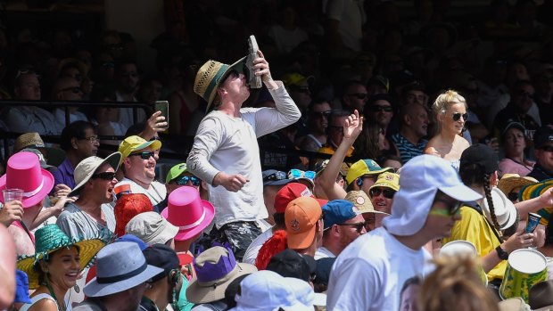 A man in the crowd at the MCG does a 'shoey'. 