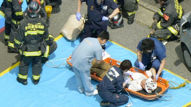 A passenger receives medical treatment from rescue workers after their Shinkansen bullet train made an emergency stop.