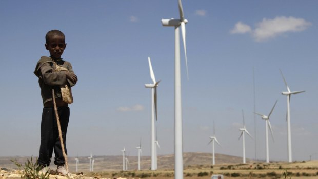 A child stands in front of wind turbines at the Ashegoda Wind Farm in Ethiopia.