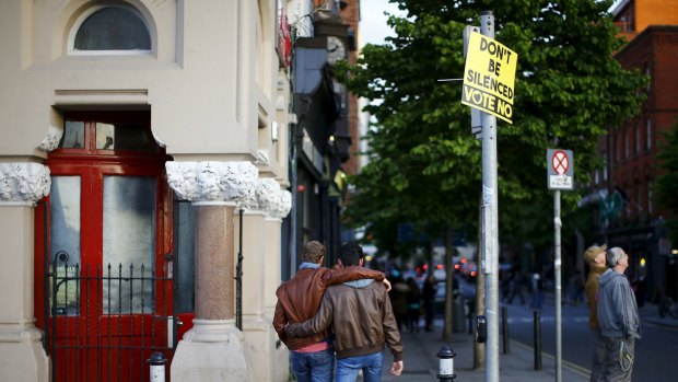 Men walk past a no vote campaign poster in central Dublin as Ireland holds a referendum on gay marriage.