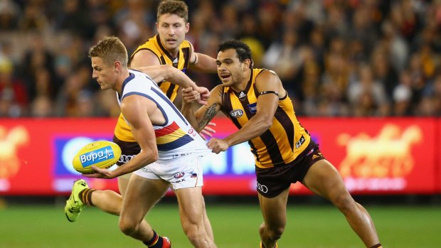 Hawthorn's Cyril Rioli hangs on to David Mackay of the Crows.
