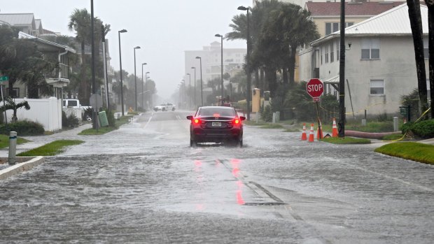 A car makes its way up a flooded street in Jacksonville Beach, Florida.