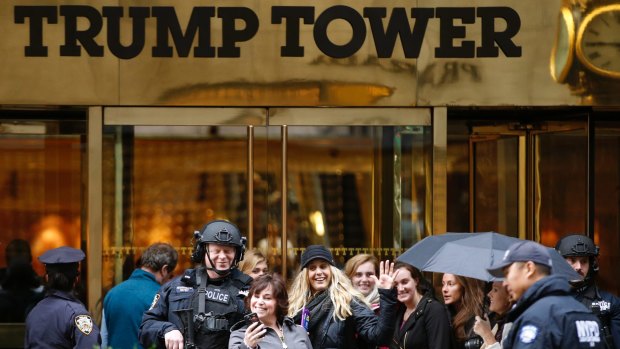 People stop for a selfie with a heavily-armed New York City police officer at the main, Fifth Avenue entrance to Trump Tower in New York on Tuesday.