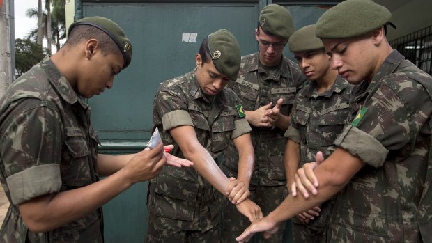 Army soldiers apply insect repellent as they prepare for a clean-up operation against the Aedes aegypti mosquito in Sao Paulo. 