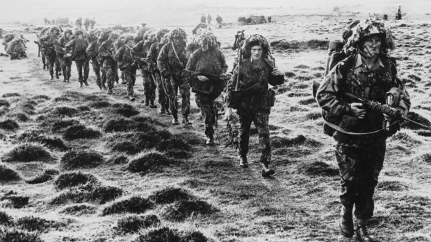 A line of British soldiers in camouflage advancing during the Falklands War. 