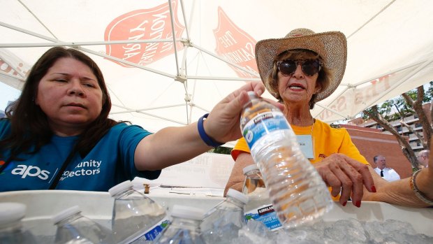 Salvation Army volunteers  restock a cooler with bottles of water at a hydration station in Phoenix. 