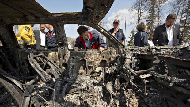 Prime Minister Justin Trudeau looks into a burned car while visiting neighbourhoods devastated by the wildfire in Fort McMurray.
