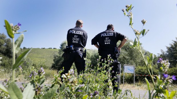 Police officers stand where a 17-year-old from Afghanistan was shot after wielding an axe and attacking travellers.