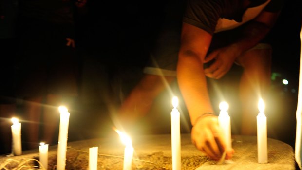 A candlelight vigil is held in the street where eight children died in a multiple stabbing in the suburb of Manoora.
