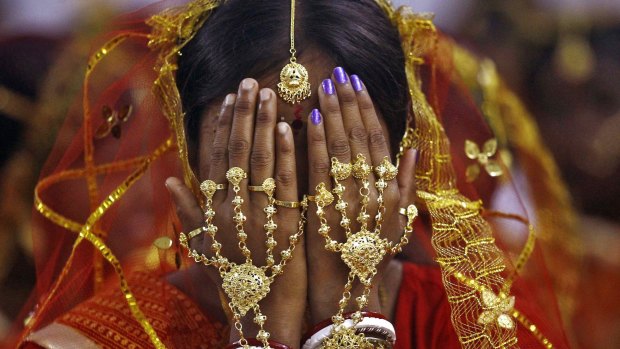 An Indian bride covers her face as she waits to take her wedding vows.
